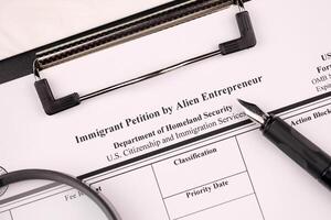 I-526 Immigrant Petition by Alien Entrepreneur blank form on A4 tablet lies on office table with pen and magnifying glass photo