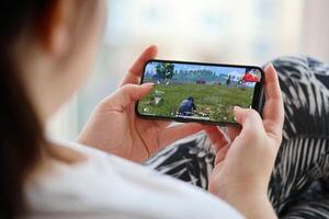PUBG PlayerUnknowns Battlegrounds mobile iOS game on iPhone 15 smartphone screen in female hands during mobile gameplay photo