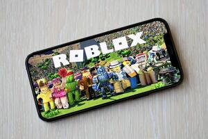 Roblox mobile iOS game on iPhone 15 smartphone screen on wooden table during mobile gameplay photo