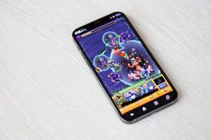 Monster Strike mobile iOS game on iPhone 15 smartphone screen on wooden table during mobile gameplay photo