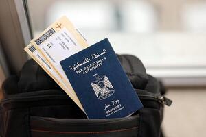 Blue Palestinian Authority passport with airline tickets on touristic backpack close up photo