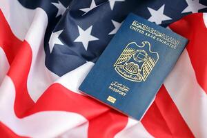 Blue United Arab Emirates passport on United States national flag background close up photo