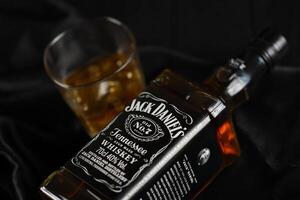 KYIV, UKRAINE - MAY 4, 2022 Jack Daniels original alcohol bottle on wooden table with black fabric photo