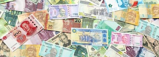 Many banknotes of different currency. Background of big amount of random money bills photo