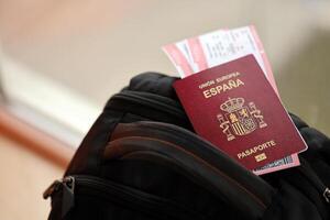 Red Spanish passport of European Union with airline tickets on touristic backpack photo