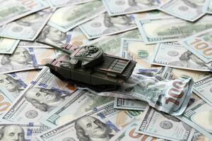 Tank on crumpled hundred dollar bills banknotes. Background of war funding and military support photo