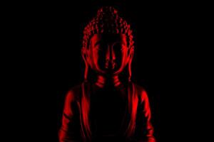 Buda purnima y vesak día concepto, rojo Buda estatua con bajo llave ligero en contra profundo negro antecedentes foto