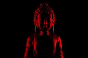 Buddha Purnima and Vesak day concept, Red Buddha statue with low key light against deep black background photo