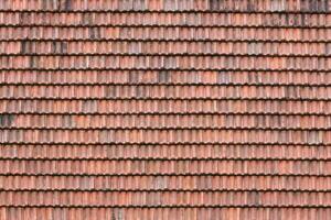 Close up of red terracotta roof shingles with some mildew. Background texture of roofing material photo