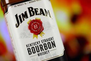 KYIV, UKRAINE - MAY 4, 2022 Jim Beam original alcohol bottle on wooden table with red fireplace photo