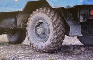 Wheel closeup in a countryside landscape with a mud road. Off-road 4x4 suv automobile with ditry body after drive in muddy road photo