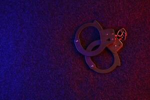 Closed handcuffs on the dark surface at night with police car lights high contrast photo