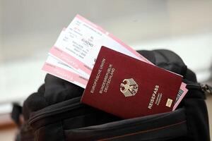 Red German passport of European Union with airline tickets on touristic backpack photo