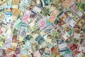 Many banknotes of different currency. Background of big amount of random money bills photo