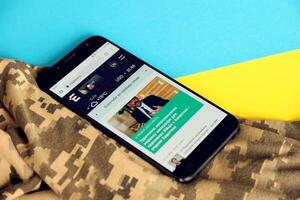 KYIV, UKRAINE - 4 MAY, 2023 Espreso TV ukrainian news portal on smartphone screen with ukrainian flag and camouflage fabric photo