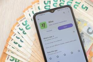 TERNOPIL, UKRAINE - AUGUST 3, 2023 Wise application on screen on modern smartphone and many bills of euro currency photo