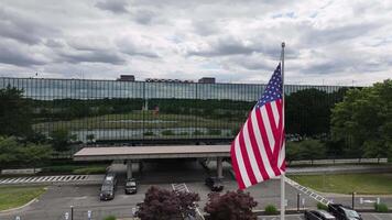 patriottico scena. americano bandiera agitando nel davanti di aziendale ufficio costruzione. con orgoglio visualizzato bandiera nel attività commerciale centro con rispecchiato riflessi. video