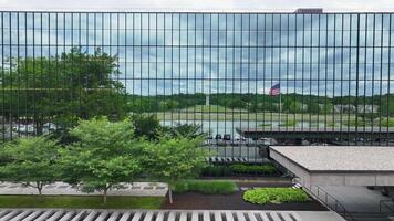 patriottisch tafereel. Amerikaans vlag golvend in voorkant van zakelijke kantoor gebouw. trots weergegeven vlag in bedrijf centrum met gespiegeld reflecties. video