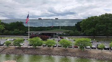 patriotisch Szene. amerikanisch Flagge winken im Vorderseite von korporativ Büro Gebäude. stolz angezeigt Flagge im Geschäft Center mit gespiegelt Reflexionen. video