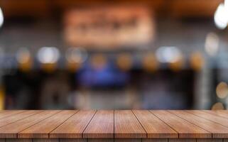 Empty wooden table top with lights bokeh on blur restaurant background photo