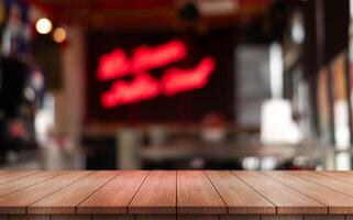 Empty wooden table top with lights bokeh on blur restaurant background photo