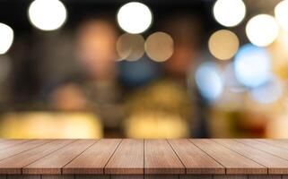 Empty wooden table top with lights bokeh on blur restaurant background photo