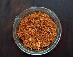 Dried shredded carrots in a glass jar on a dark wooden background photo