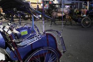 un pedicab o javanés bicitaxi conductor es esperando para pasajeros en el malioboro zona a noche foto