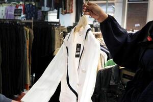 un cliente es elegir desde un fila de ropa colgando en un Tienda estante. adecuado para Moda y Al por menor conceptos foto