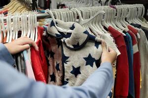 un cliente es elegir desde un fila de ropa colgando en un Tienda estante. adecuado para Moda y Al por menor conceptos foto