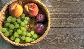 Top view of fruit in wicker basket on natural wood surface photo