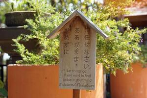 Japanese style wooden sign with messages written in Japanese. English and Thai, which is translated as written let things go if you want to find peace in your mind, to give ideas to readers. photo