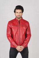 handsome pakistani young man in red biker leather jacket on white background, closeup, full height, smiling poses photo