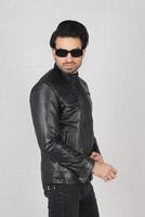 full - length portrait of young man in leather jacket and sunglasses posing in studio photo