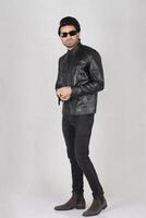 full - length portrait of young man in leather jacket and sunglasses posing in studio photo