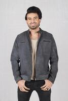 handsome young man wearing a leather jacket and posing in the studio. photo