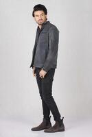 handsome young man wearing a leather jacket and posing in the studio. photo