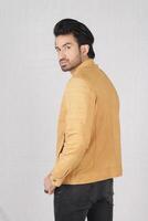 studio shot of young handsome indian man wearing brown leather jacket against white background photo