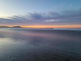 Sunset at Playa de Famara, Lanzarote, paints the sky with vibrant hues, casting a mesmerizing glow over the horizon. Breathtaking sight that captures the essence of tranquility and natural beauty. photo