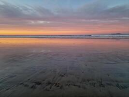 puesta de sol a playa Delaware famara, lanzarote, pinturas el cielo con vibrante matices, fundición un fascinante resplandor terminado el horizonte. asombroso visión ese capturas el esencia de tranquilidad y natural belleza. foto
