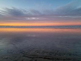 Sunset at Playa de Famara, Lanzarote, paints the sky with vibrant hues, casting a mesmerizing glow over the horizon. Breathtaking sight that captures the essence of tranquility and natural beauty. photo