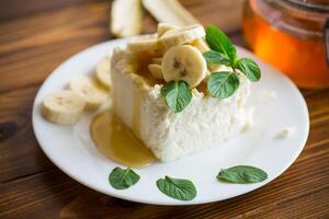 Portion of homemade milk curd with banana slices and honey photo