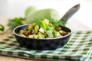 Sliced zucchini fried with onions and herbs in a frying pan photo