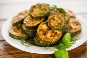 zucchini fried in circles with spices and herbs, in a plate . photo