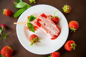 homemade strawberry ice cream on a stick in a plate with strawberries photo