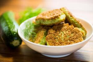 fried zucchini pancakes with herbs, in a plate . photo