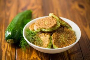 fried zucchini pancakes with herbs, in a plate . photo