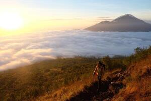 Asian Adventure, Man Model on Mountain Summit, Carrying Hiking Gear under Blue Sky above Ocean of Clouds photo