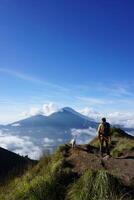 Asian Adventure, Man Model on Mountain Summit, Carrying Hiking Gear under Blue Sky above Ocean of Clouds photo