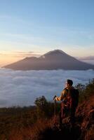 Skyward Summit, Asian Model on Mount Batur, Carrying Hiking Gear amidst Cloud Ocean photo